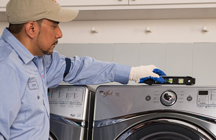 A person installs a new washer in a laundry room. It checks if the device is level.