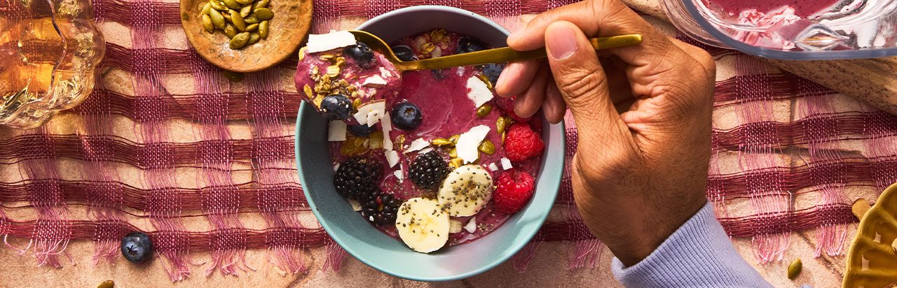 A scone on a napkin with a small container of herb butter. 