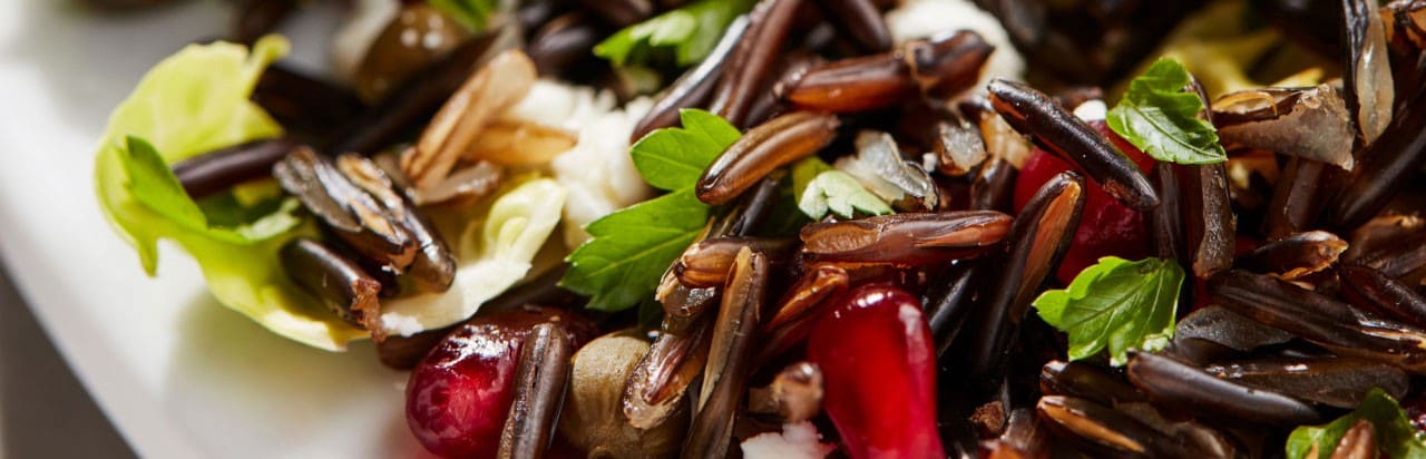 A salad of shaved Brussels sprouts, pomegranates and wild rice garnished with fresh herbs.