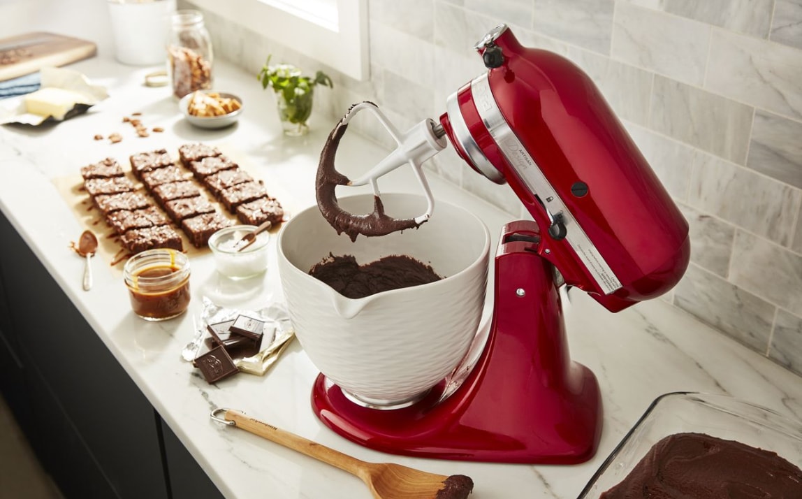 Batteur sur socle rouge pomme d'amour KitchenAid avec bol en céramique blanc rempli de pâte à brownie
