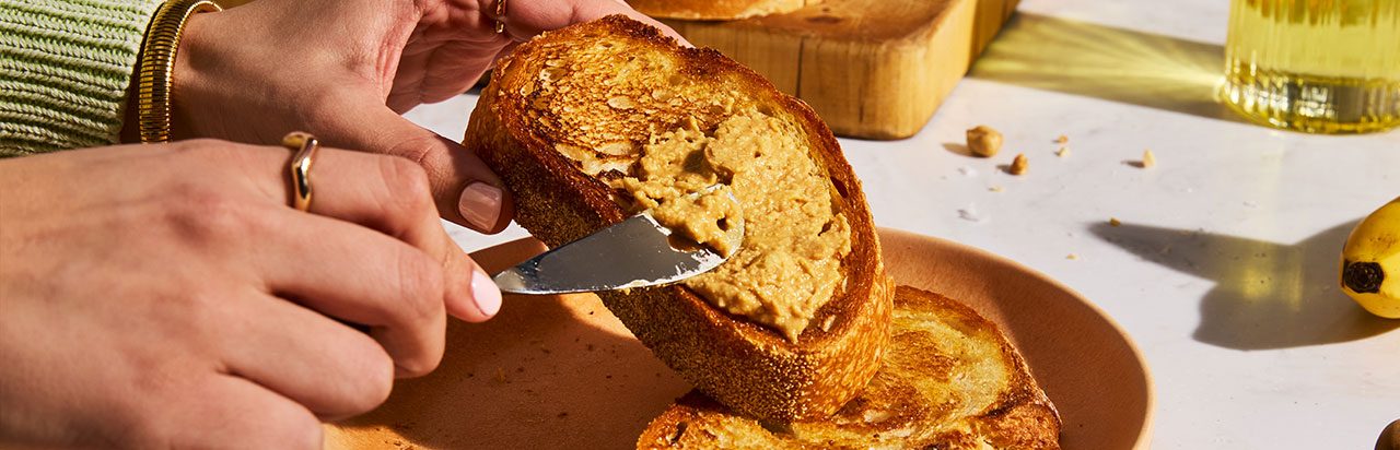 A scone on a napkin with a small container of herb butter. 