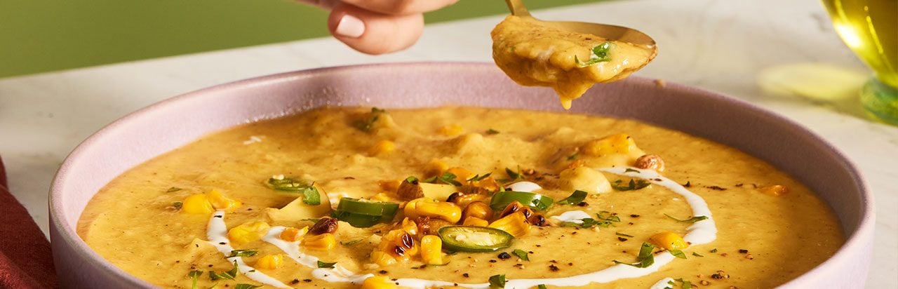 A scone on a napkin with a small container of herb butter. 
