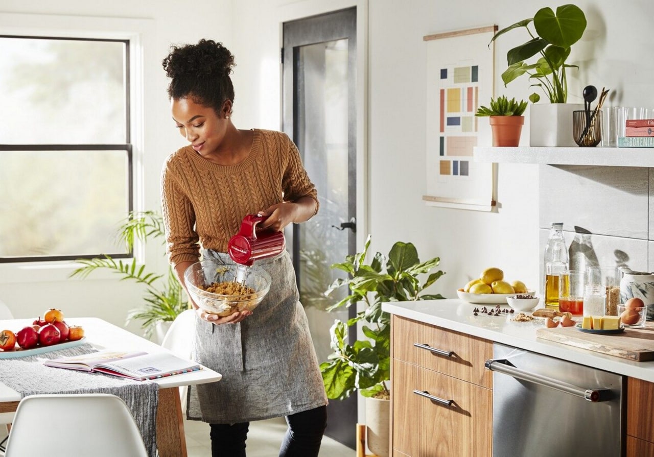 Une femme utilise un batteur à main pour mélanger une recette