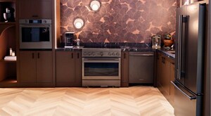 An elegant kitchen with KitchenAid appliances, including a wall oven, range, dishwasher, and refrigerator. There's a coffee maker and other items on the counter. A KitchenAid stand mixer sits on a shelf. 