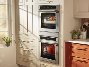  An opened KitchenAid dishwasher with the racks pulled out. The racks are filled with plates, bowls, mugs, cutlery, and other various items. 
