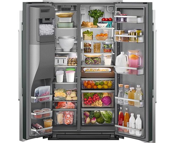 Un réfrigérateur côte à côte KitchenAid ouvert. À l'intérieur du réfrigérateur se trouvent des bacs à légumes remplis de fruits et légumes, des fruits et légumes sur des étagères, un gâteau sur un présentoir, des boissons, des condiments, des herbes fraîches et autres aliments.