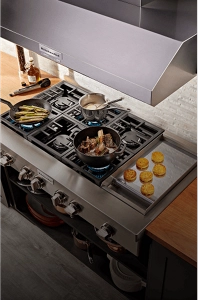 A gas cooktop with three pans of food cooking on it