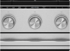 A close up on the knobs of a stainless steel oven.