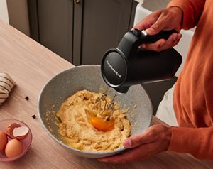 Une personne utilisant le batteur à main sans fil KitchenAid Go™ pour battre les jaunes d'œufs en une pâte.